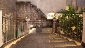 A stone staircase with metal railings, leading to a landing with a bench and potted plants. - Appartamento Terrazza Tasso (Sorrento)