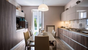 A modern kitchen with a dining area, featuring a large window, a dining table with chairs, and a pendant light. - Appartamento Terrazza Tasso (Sorrento)