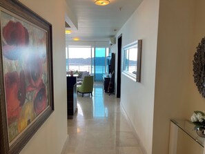 Un pasillo con un cuadro grande, una mesa de cristal y vistas al mar.