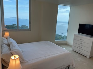 Un dormitorio con cama, lámparas de noche, cómoda y televisor.