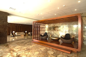 Un hall con mostrador de recepción, zona de estar y pared de piedra.