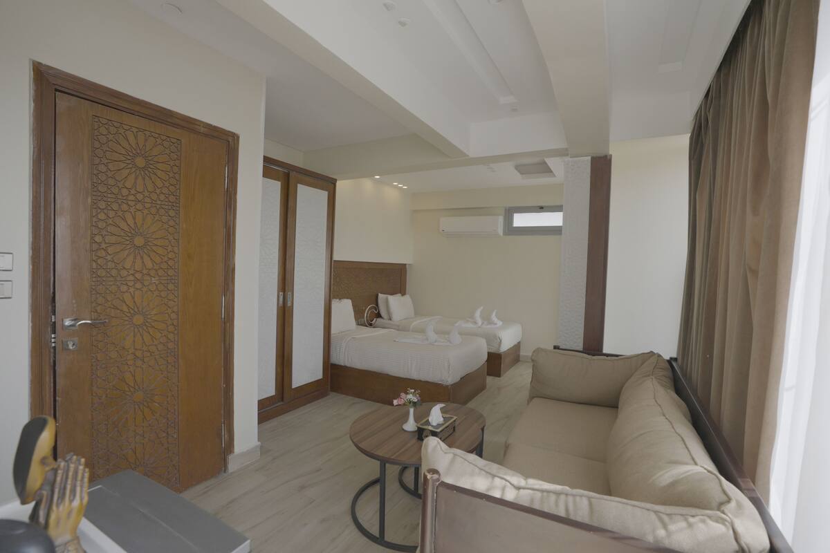 A hotel room with a bed, a sofa, a round table, and a decorative door.