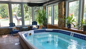 A hot tub with a 3 ft depth, surrounded by wooden decking, stone walls, and potted plants.