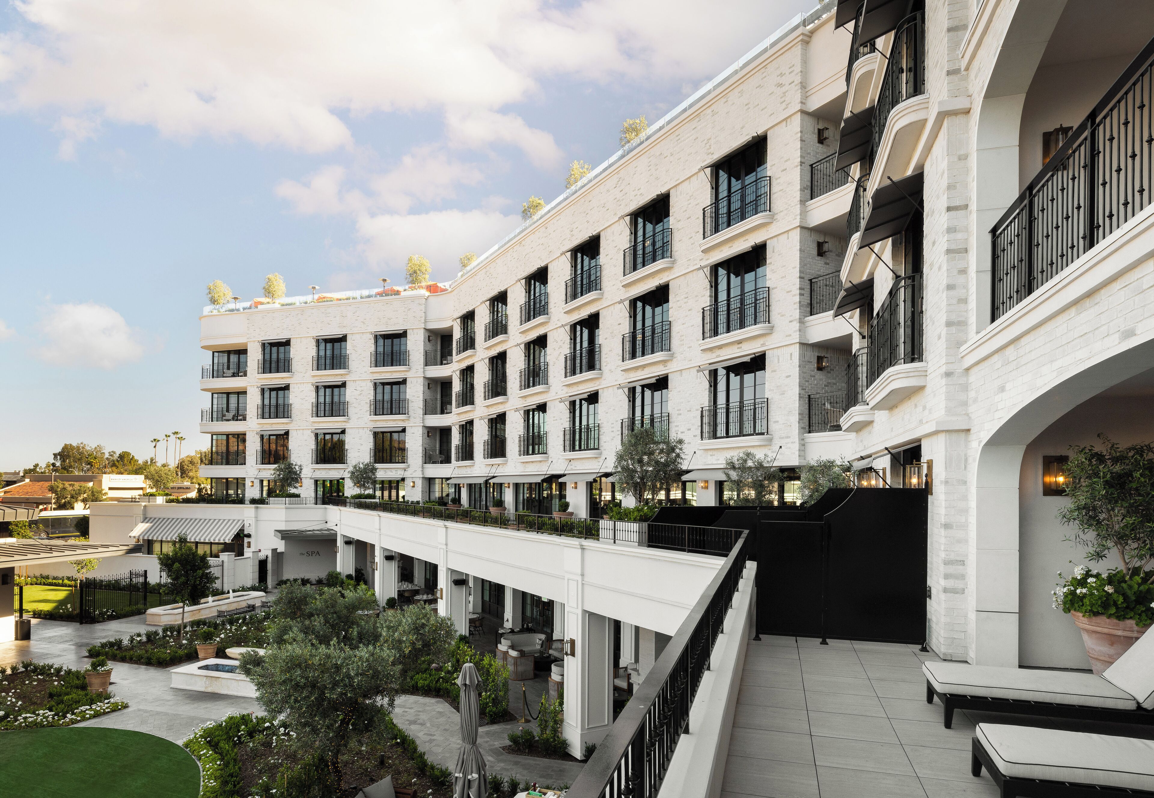 A multi-story hotel with a central courtyard, outdoor seating, and a spa area.