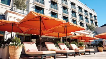 Una piscina al aire libre, camas de piscina con cargo, sombrillas