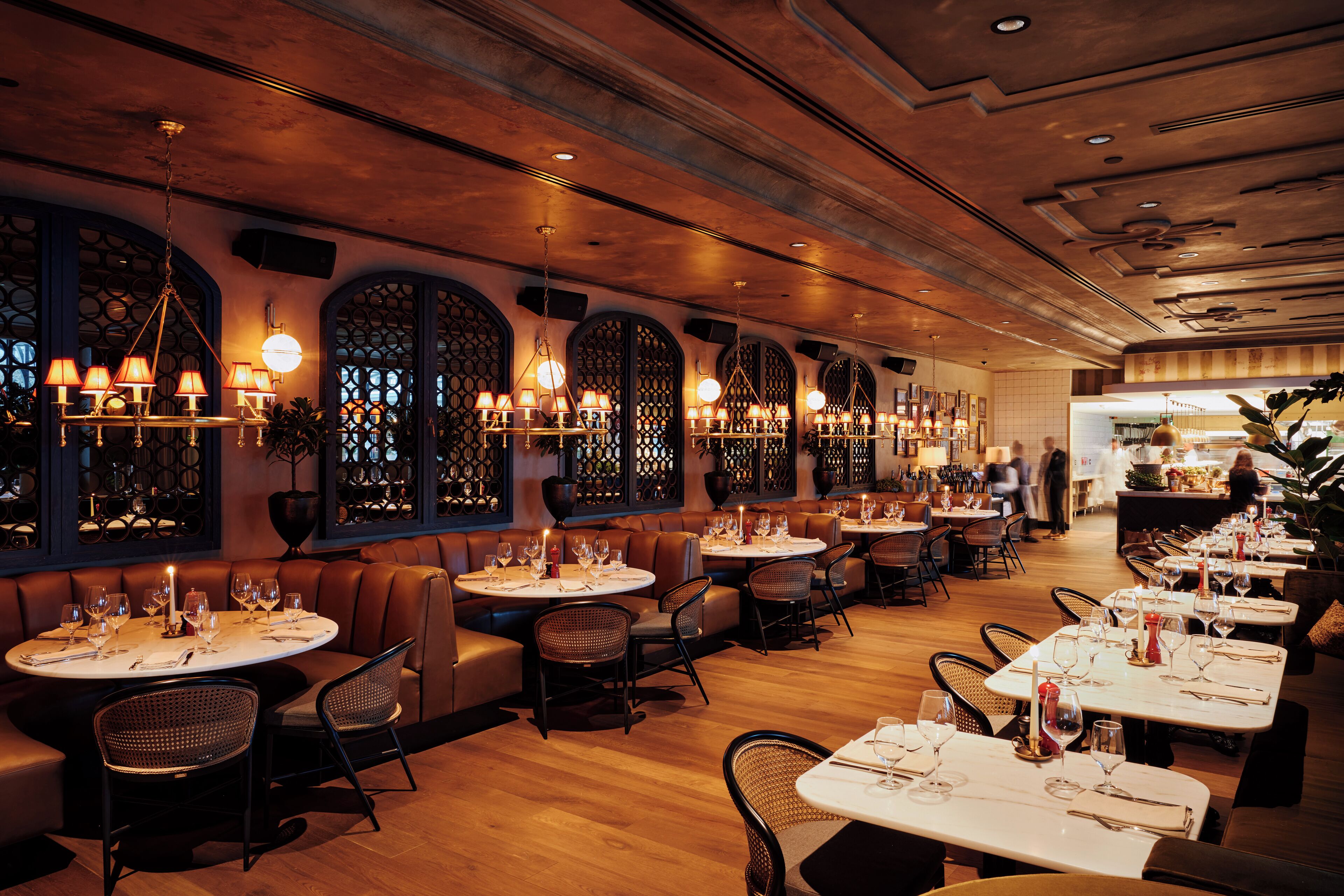 A restaurant with round tables, leather booths, and a warm ambiance.