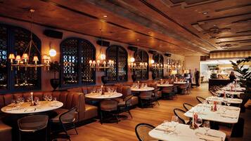 A restaurant with round tables, leather booths, and a warm ambiance.
