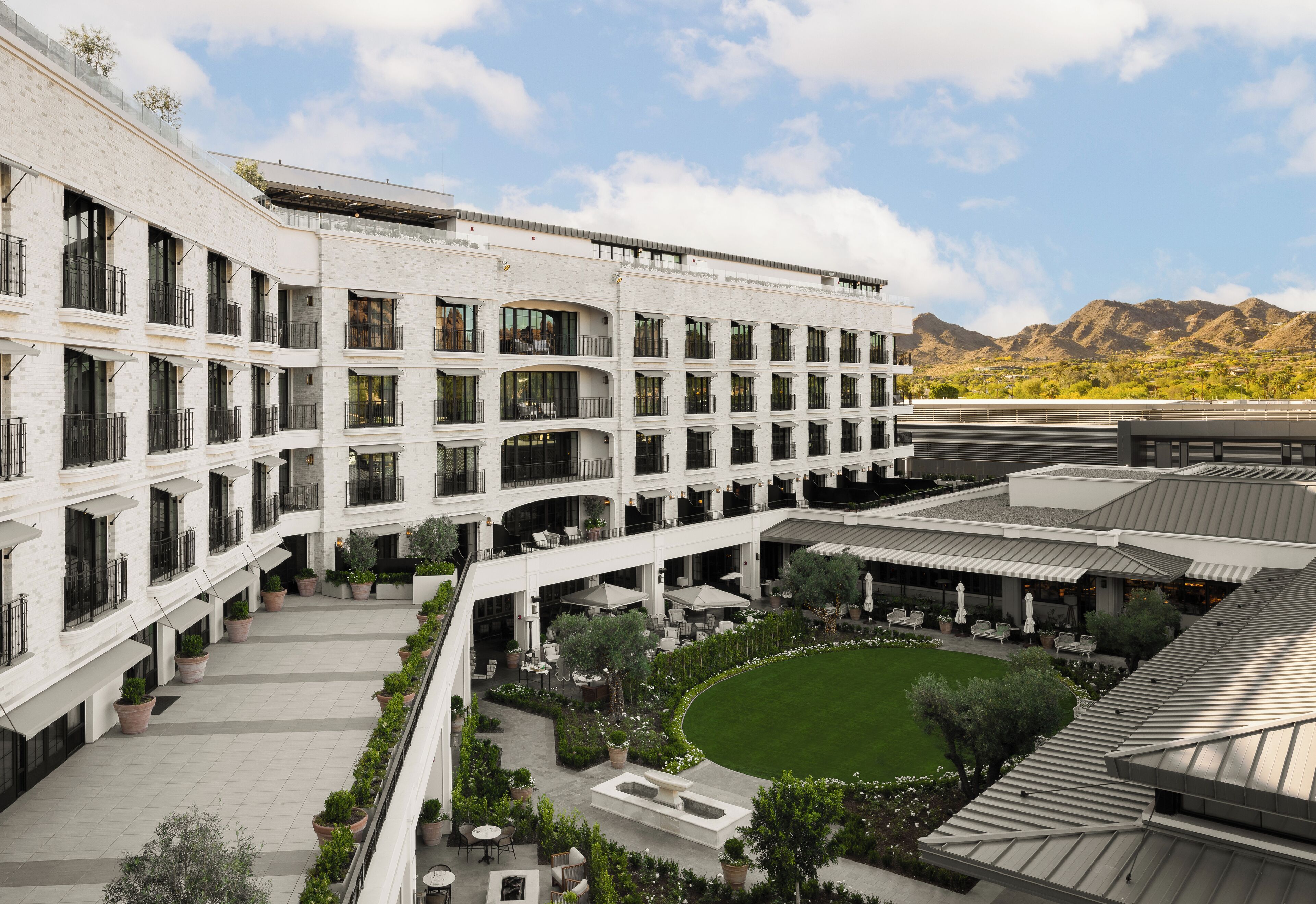 Hotel de varios pisos con un patio que incluye asientos al aire libre y áreas verdes.