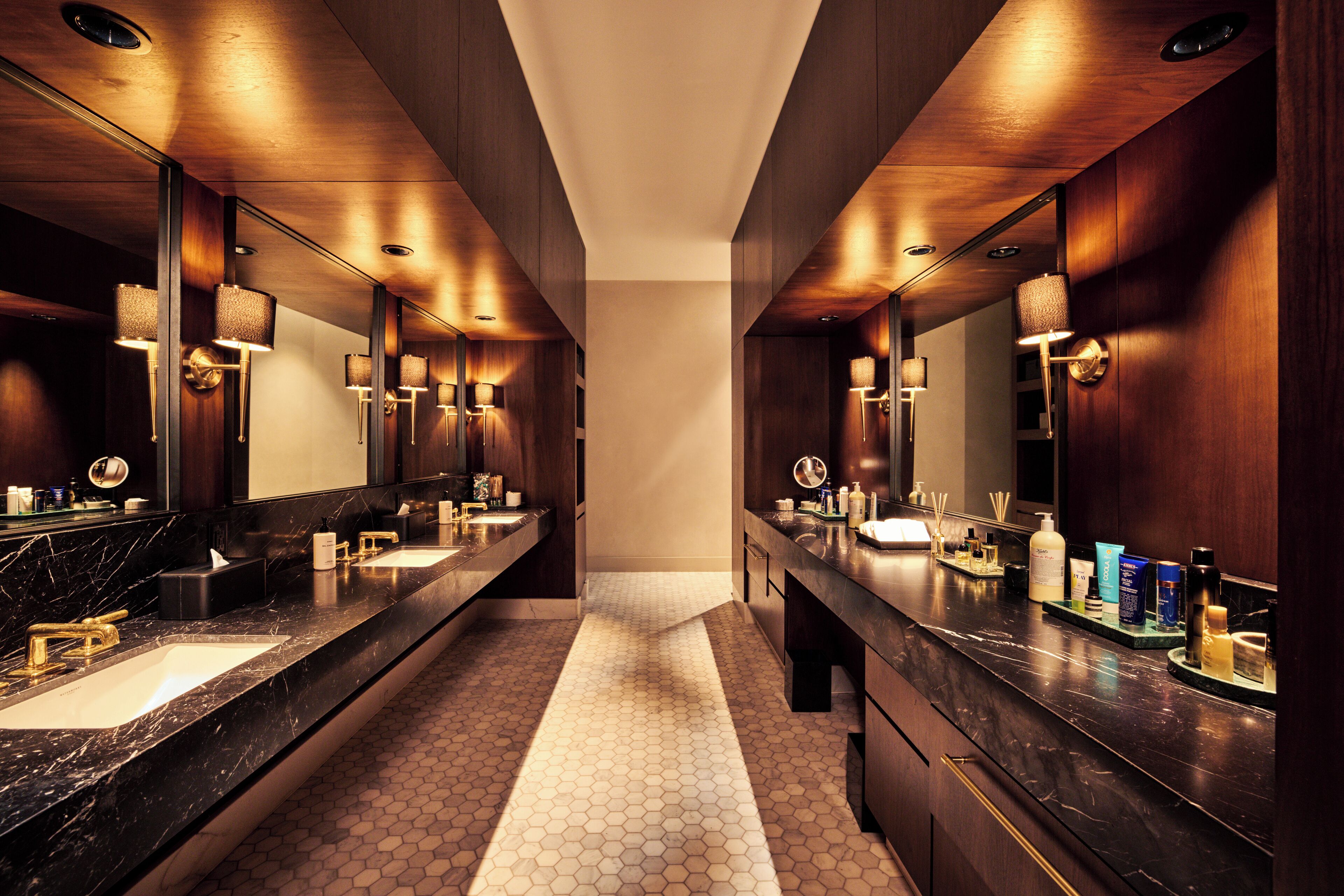 Une salle de bain moderne avec des meubles en bois foncé, des comptoirs en marbre et un revêtement de sol à motifs hexagonaux.
