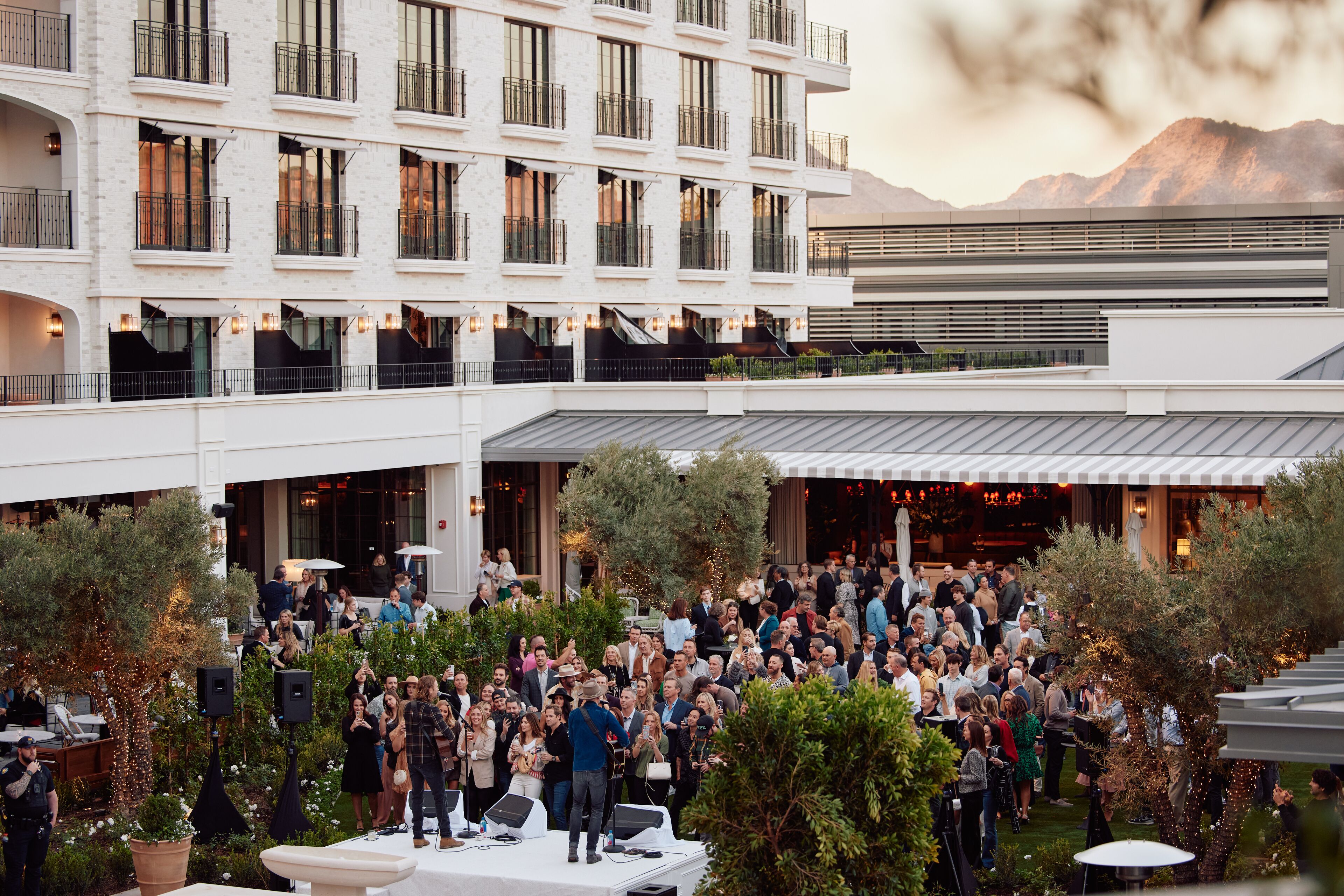 A multi-story hotel with outdoor seating areas, balconies, and a mountain backdrop.