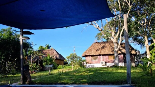 A pool area with a clear view of thatched-roof huts and surrounding greenery.
