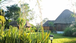 A rural setting with thatched-roof huts, lush greenery, and a clear sky.