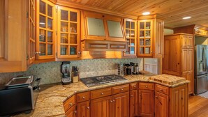Eine Küche mit Holzausstattung, einer Granitarbeitsplatte, einem Herd und einem Kühlschrank.