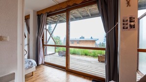 Una habitación con un gran ventanal corredero que da a una terraza de madera.