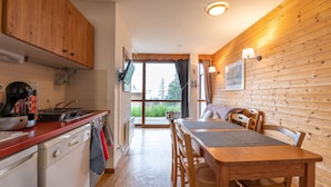 Una cocina con armarios de madera, una estufa y un lavabo. Hay una zona de comedor con una mesa y sillas.