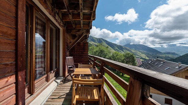 Un balcón de madera con vistas a montañas y un cielo despejado.