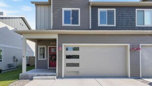 A two-story residential building with a garage, a front door, and a small front yard. - Townhome Near Bozeman Airport (Belgrade)