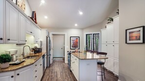 Una cocina moderna con armarios blancos, encimera de madera y una isla central.