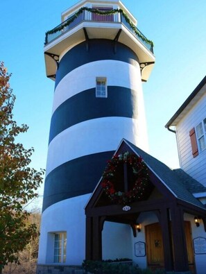 Un phare à l’extérieur rayé de noir et de blanc, doté d’une petite fenêtre et d’un porche orné d’une guirlande.