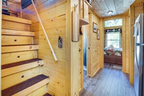 A wooden interior with a staircase, a refrigerator, and a window with curtains. - 7 Mi to Lake Lure: Mill Spring Cabin w/ Hot Tub (Mill Spring)