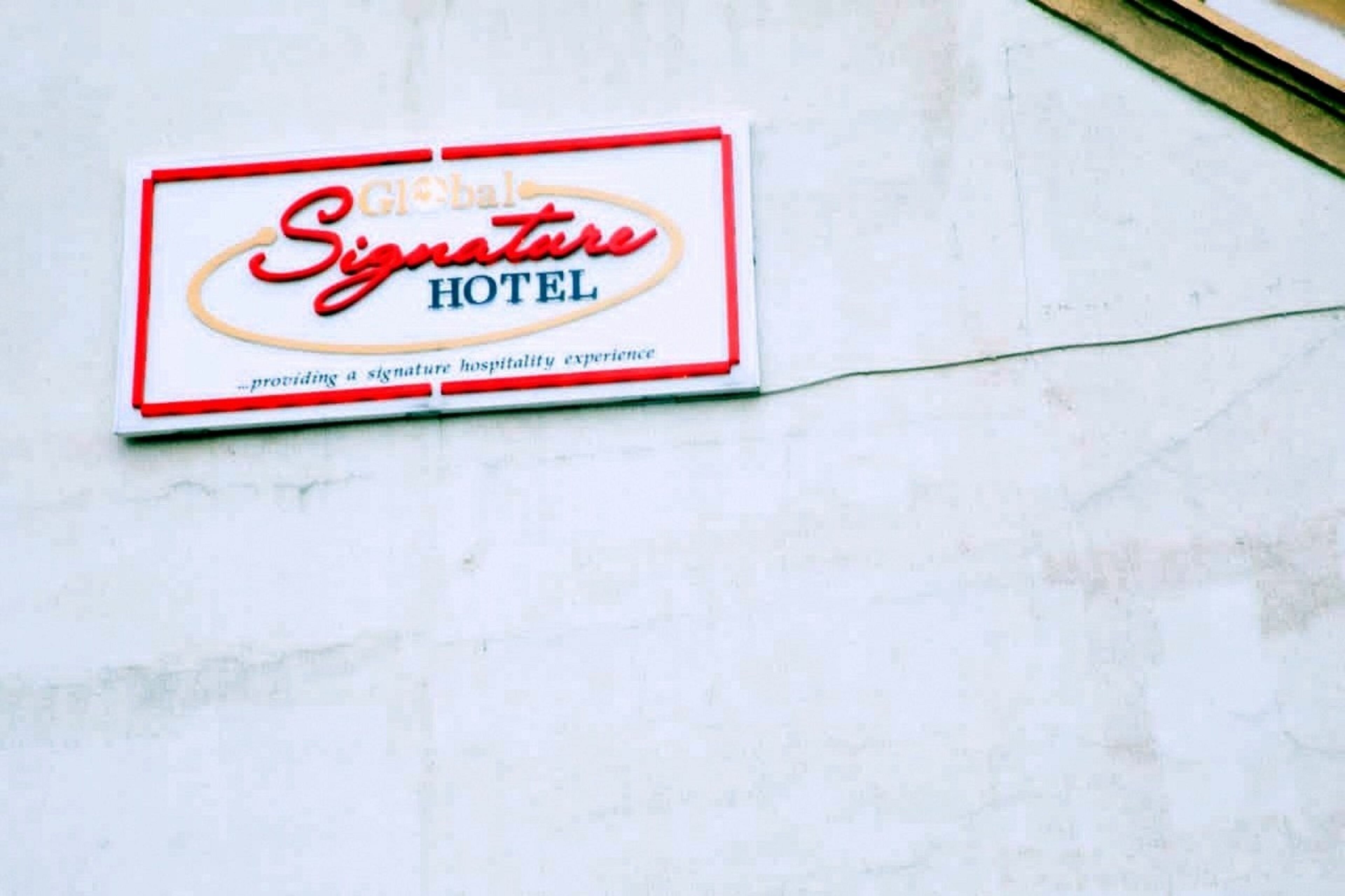 A hotel sign with the name "Signature Hotel" and a tagline "providing a signature hospitality experience."