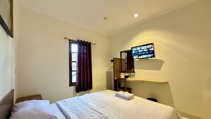 A hotel room with a bed, a desk with a computer monitor, a chair, and a window with curtains. - The Raden Patah Heritage Kota Lama (Semarang)