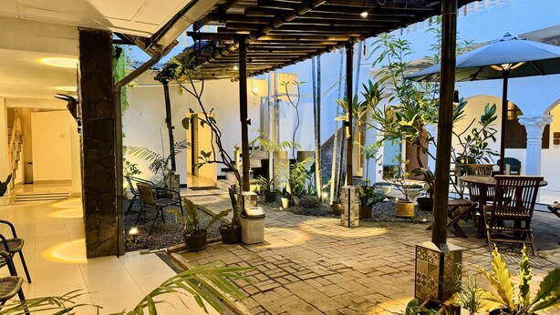 A spacious outdoor area with a pergola, potted plants, and a seating area with wooden chairs and tables. - The Raden Patah Heritage Kota Lama (Semarang)