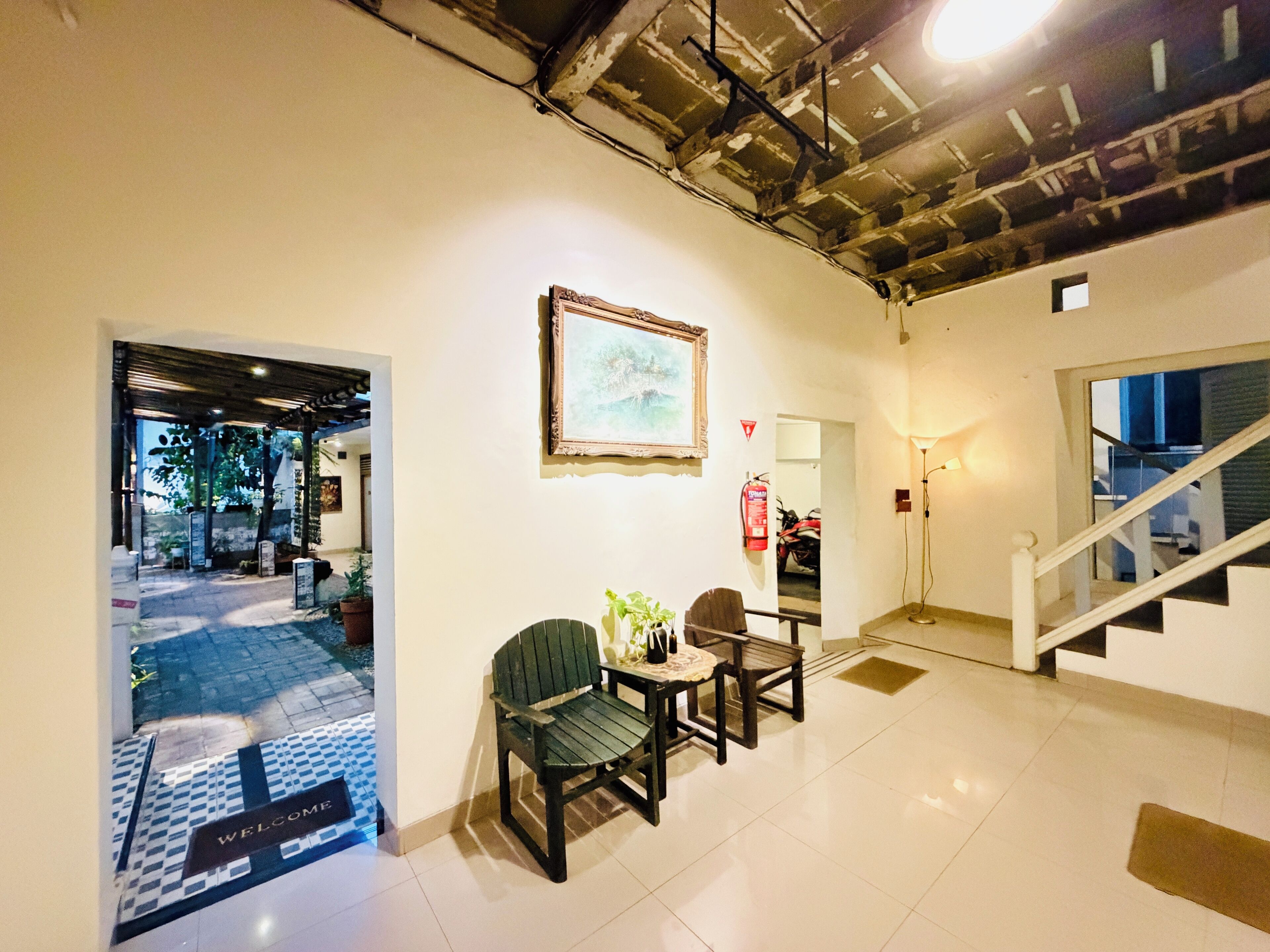 A reception area with a welcome mat, a framed picture on the wall, and a staircase leading to another floor.