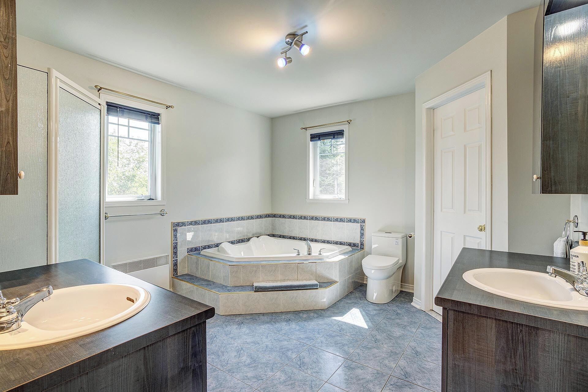 A bathroom with two sinks, a bathtub, and a toilet.