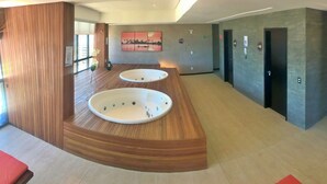 Un espace spa moderne doté de deux bains à remous et d’un comptoir d’accueil en bois.