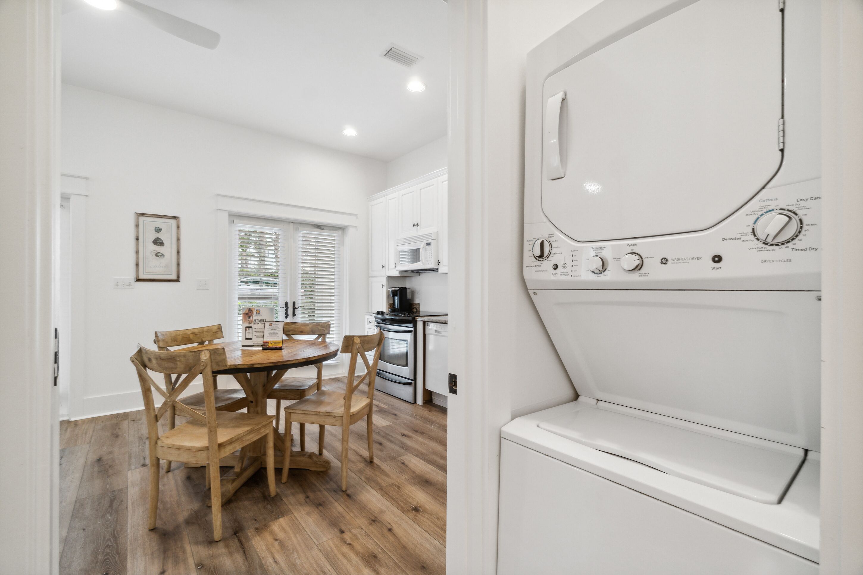 A kitchen with white cabinets, a microwave, and a dishwasher. There is a wooden dining table with chairs.