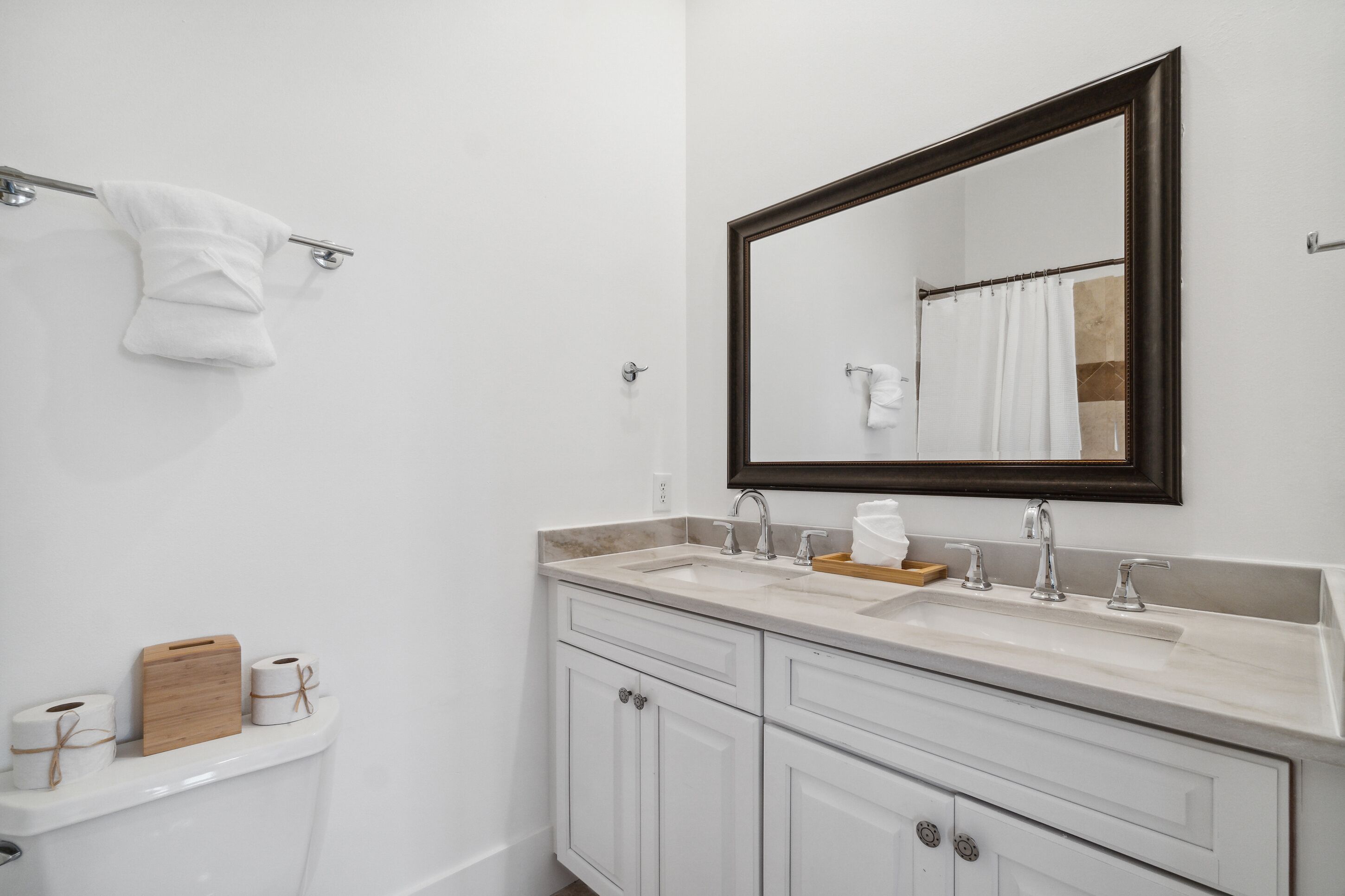 Un bagno con un lavandino bianco, due rubinetti, uno specchio e un portaserviti.