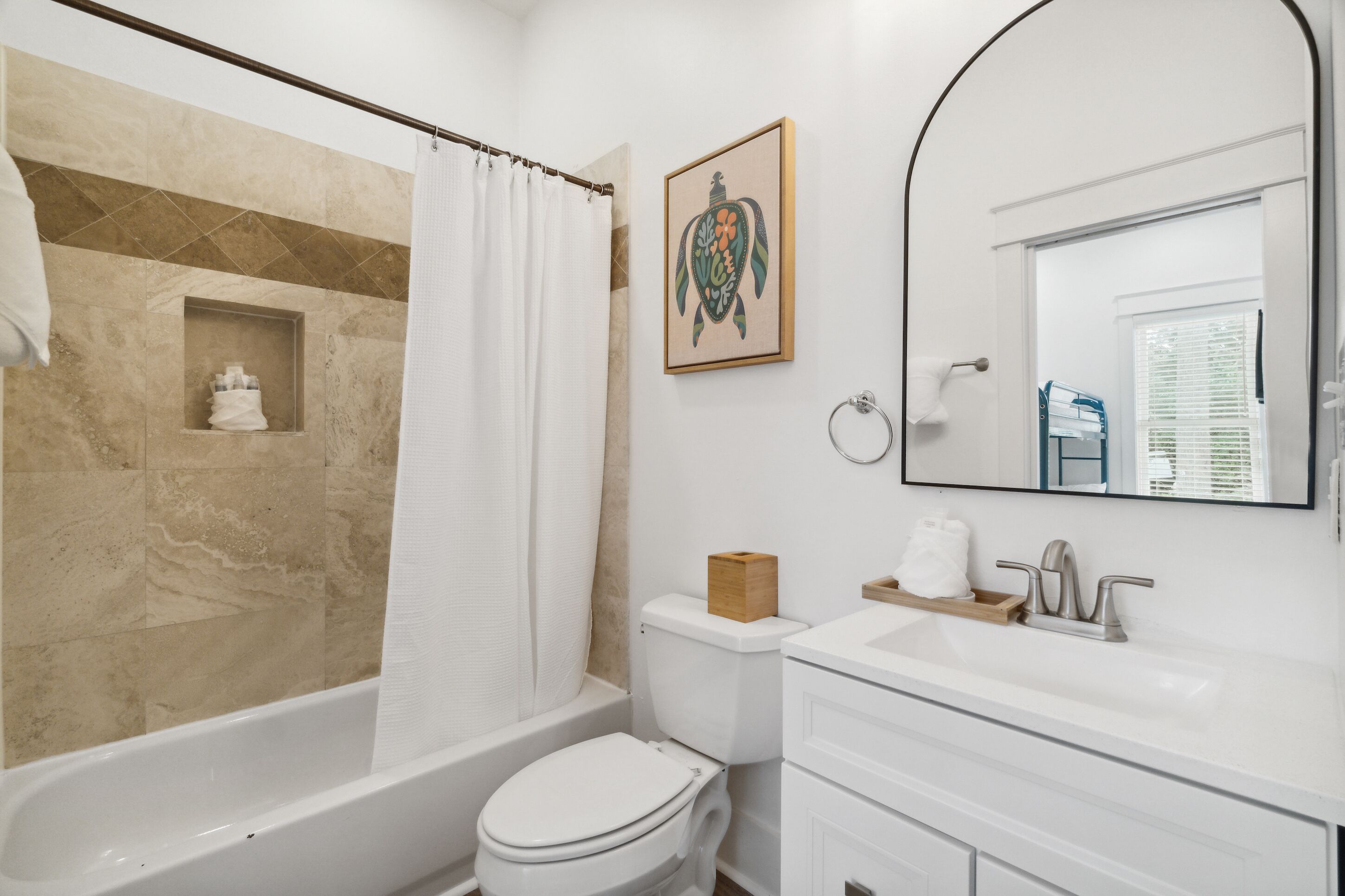 A bathroom with a bathtub, toilet, sink, and a mirror.