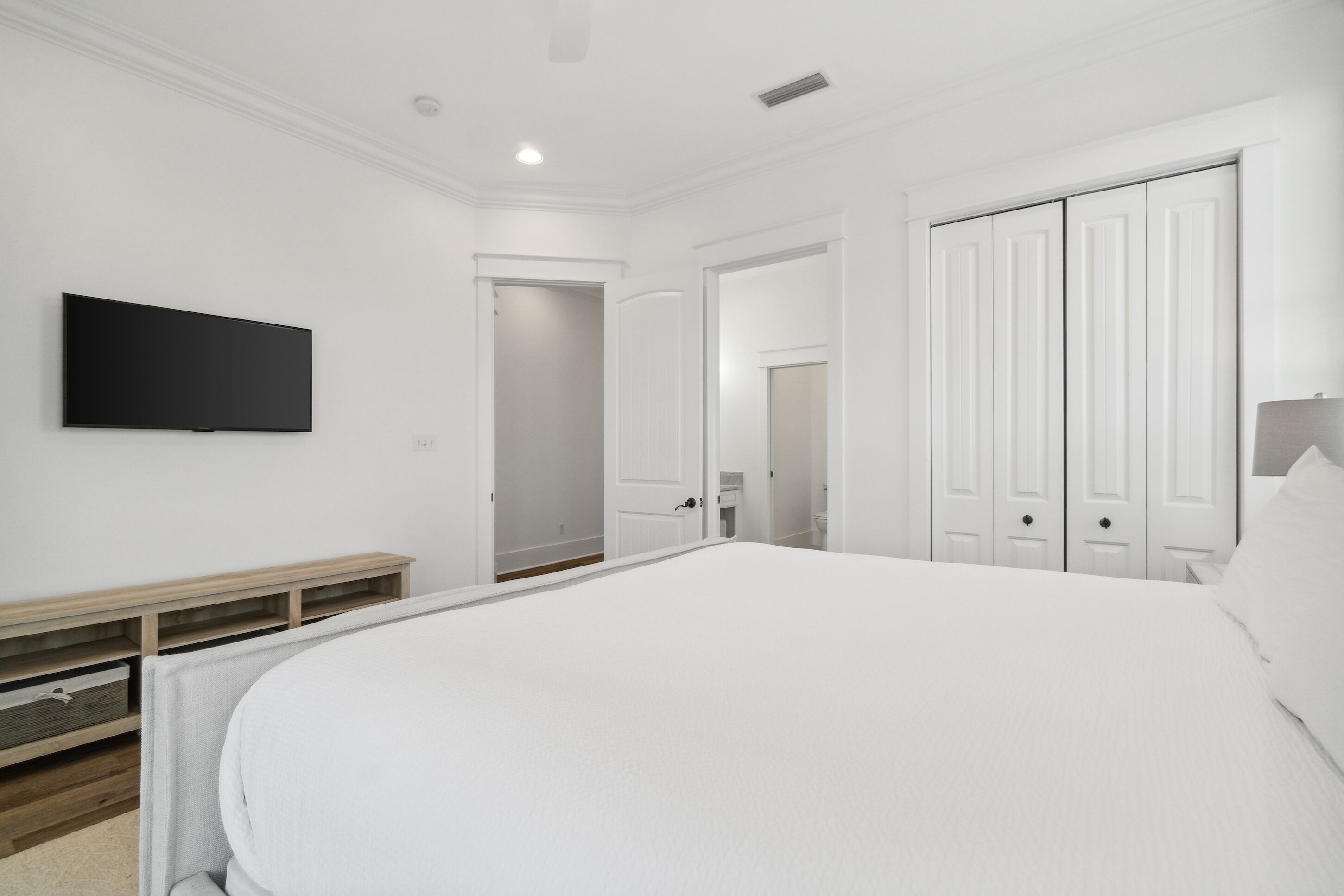 Une chambre avec un grand lit, un téléviseur fixé au mur et une armoire avec des portes coulissantes.
