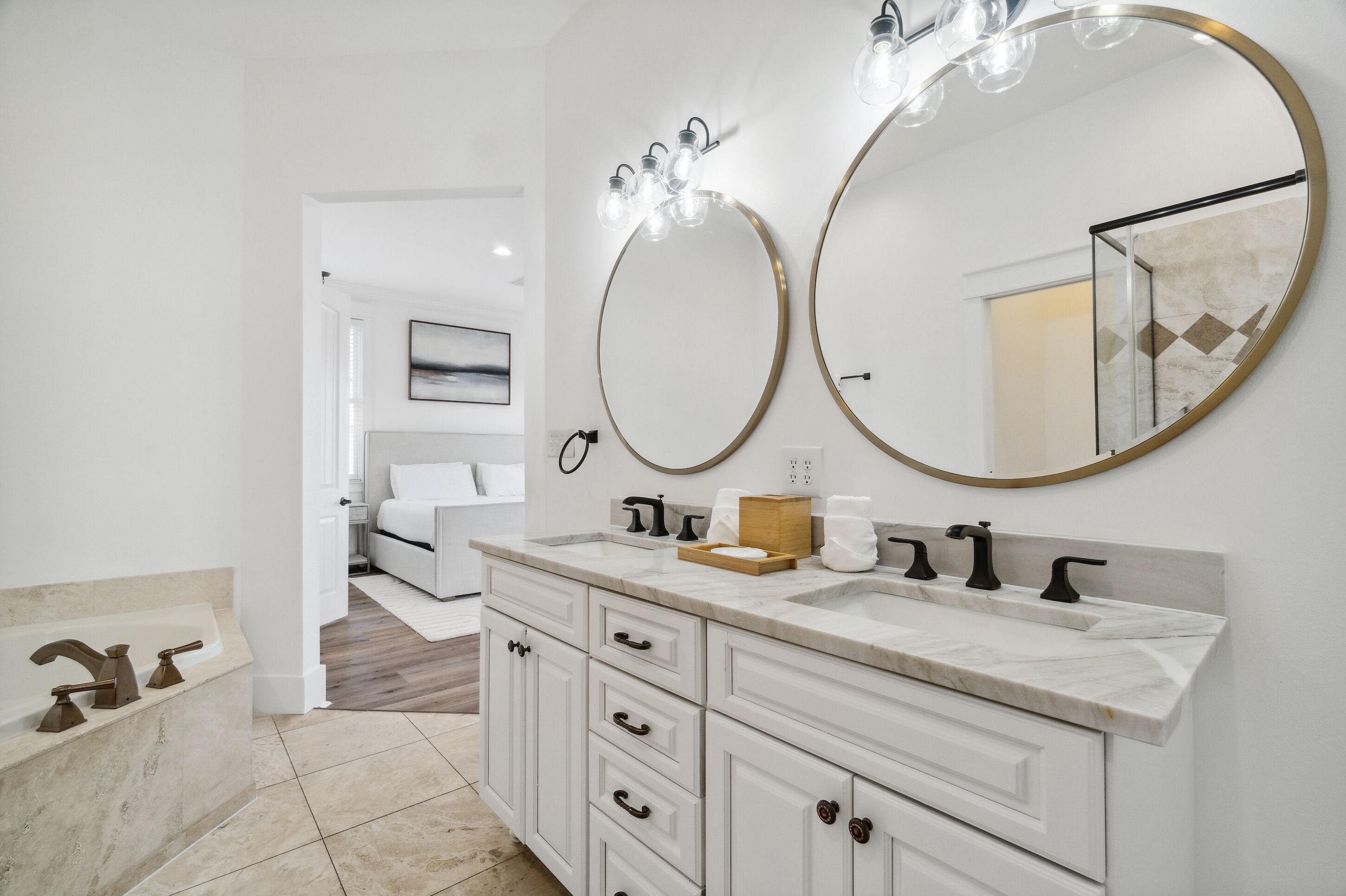 A bathroom with a double sink, two large mirrors, and a bathtub.