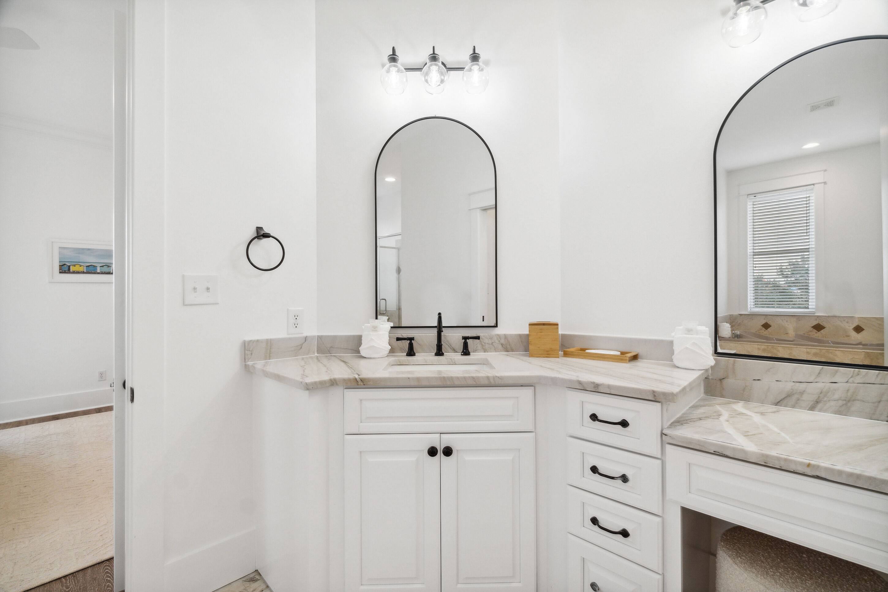 A modern bathroom with a white vanity, a large mirror, and a light fixture above the mirror.