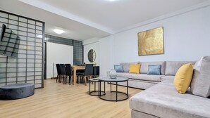Un salon moderne avec un canapé gris, une table à manger en bois et un miroir à cadre noir.