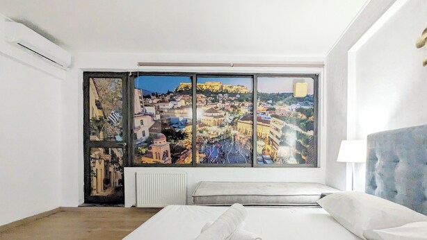 Une chambre d’hôtel dotée d’une grande fenêtre donnant sur un paysage urbain, d’un lit avec une serviette roulée et d’une tête de lit moderne.