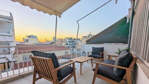 Un balcon doté de mobilier en bois et offrant une vue sur le paysage urbain au coucher du soleil.