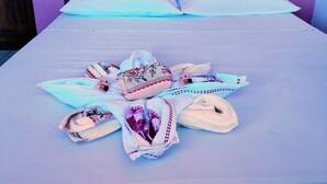 A bed with a white sheet, two pillows, and a towel arrangement on the bed. - Pousada Raysol Arraial d'Ajuda (Porto Seguro)