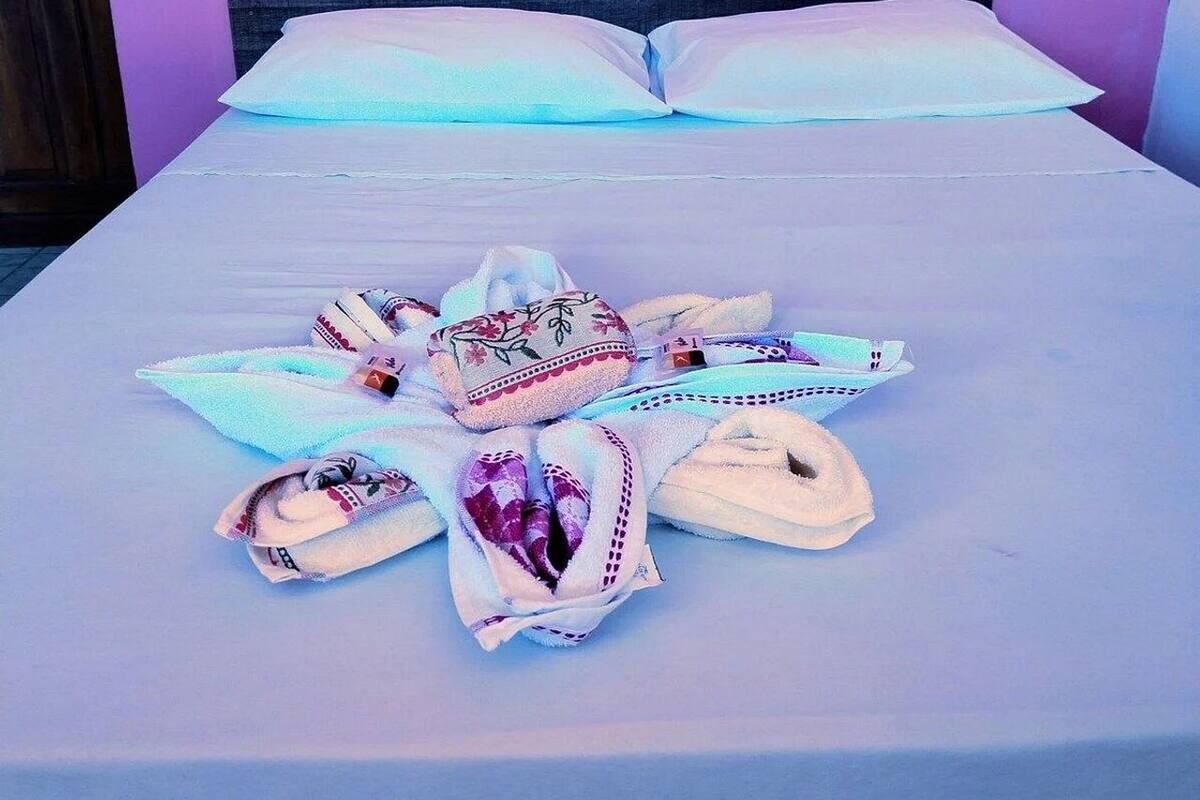 A bed with a white sheet, two pillows, and a towel arrangement on the bed.