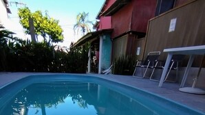 A rectangular swimming pool with clear blue water, surrounded by a concrete deck. - Pousada Raysol Arraial d'Ajuda (Porto Seguro)