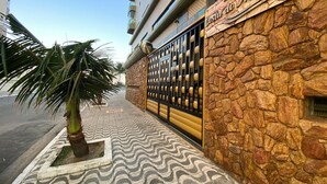 Un edificio con facciata in pietra, un cancello in metallo e una palma sullo sfondo.