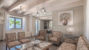 Een ruime woonkamer met een grote bank, bijpassende fauteuils, een salontafel en een eethoek in de achtergrond.