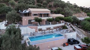 Een moderne villa met zwembad, terras en uitzicht op het omliggende landschap.