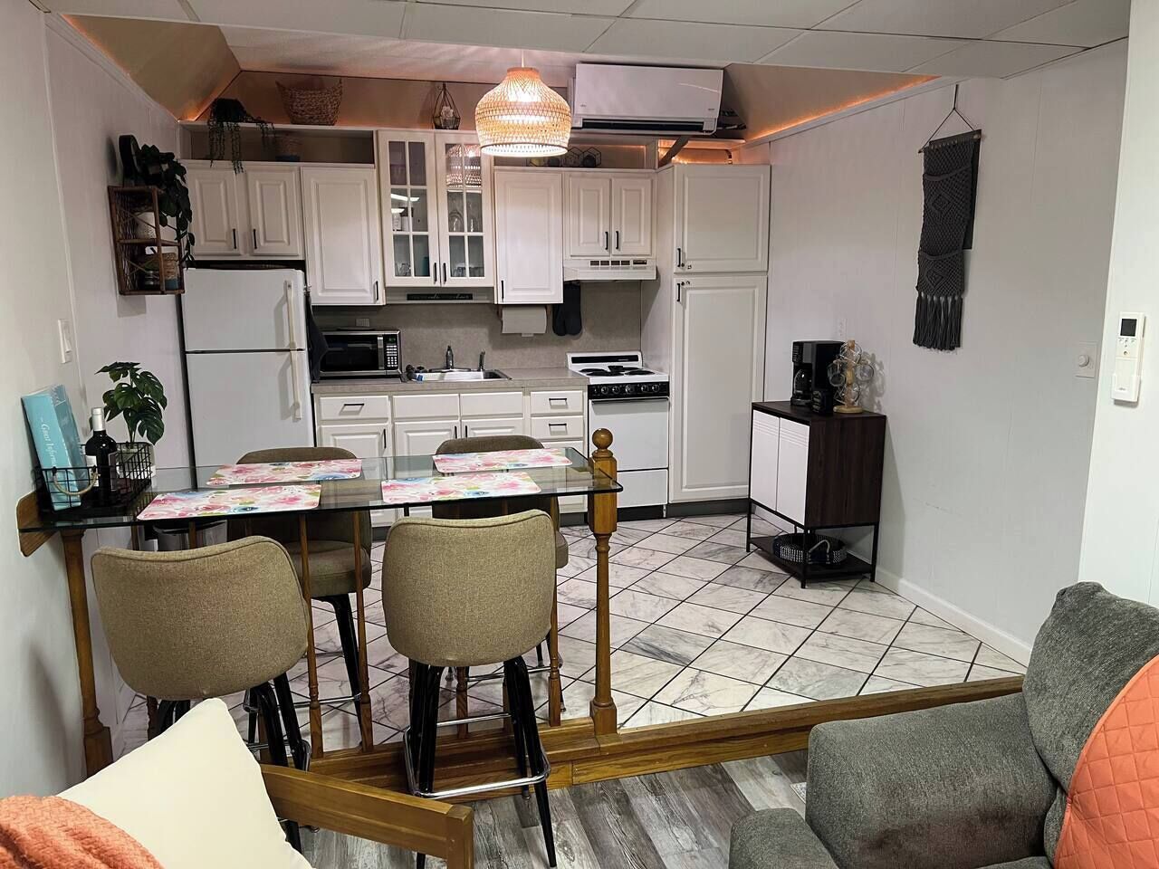 A compact kitchen with white cabinets, a dining table with chairs, and a hanging light fixture.