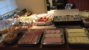 A buffet table with various food items including fruits, meats, and dairy products. - Hotel Prelude (Aalter)
