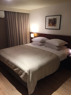A hotel room with a large bed, a nightstand with a lamp, and a framed picture on the wall. - Hotel Prelude (Aalter)