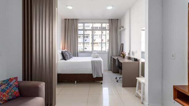 Une chambre d’hôtel moderne équipée d’un lit, d’un bureau, d’une chaise et d’une petite table.