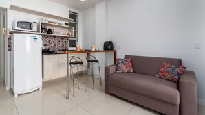 Un espace de vie compact comprenant un coin cuisine, un canapé et un petit espace bar.